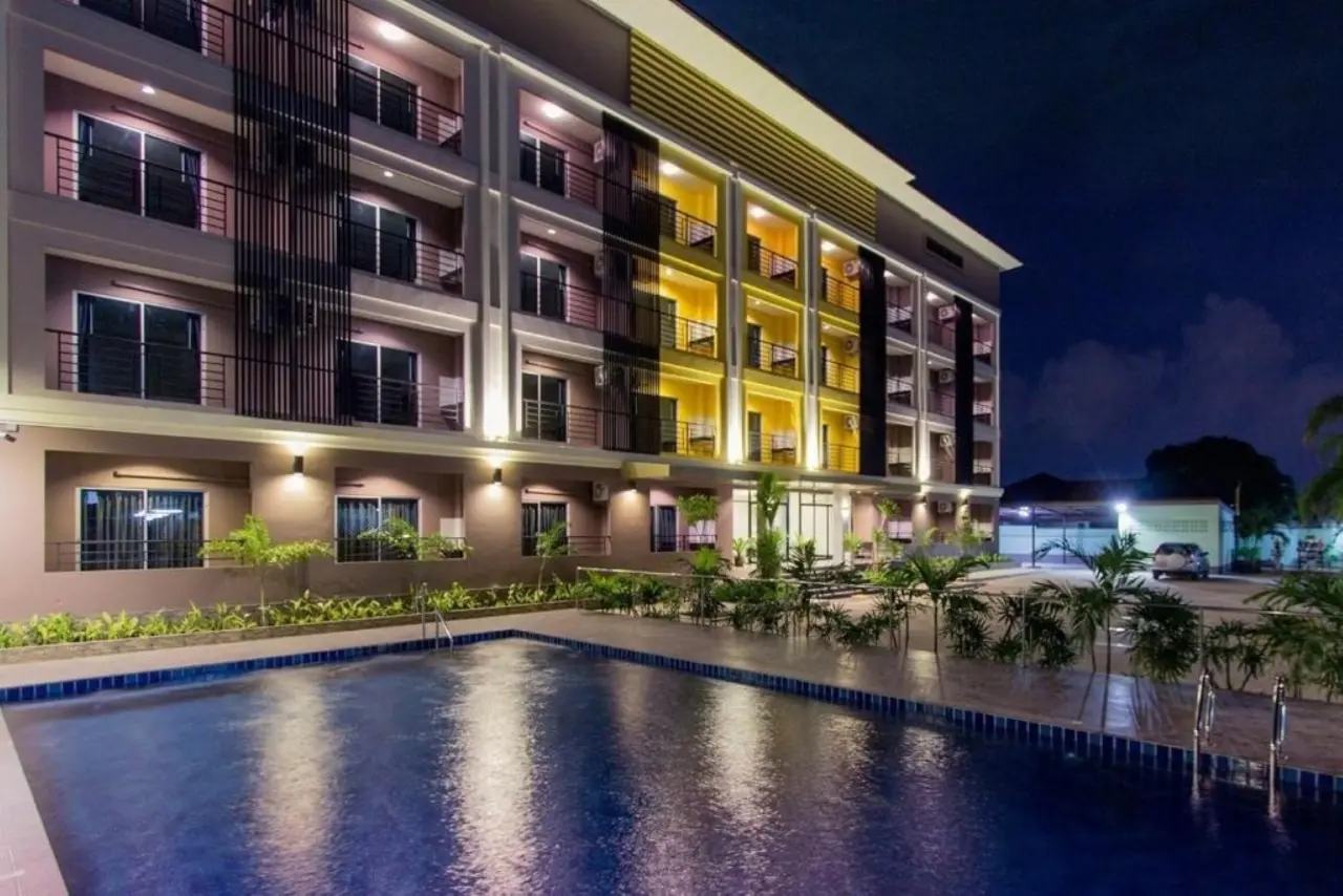 Beleuchtete Fassade der B Space Residence Pattaya mit Pool im Vordergrund.