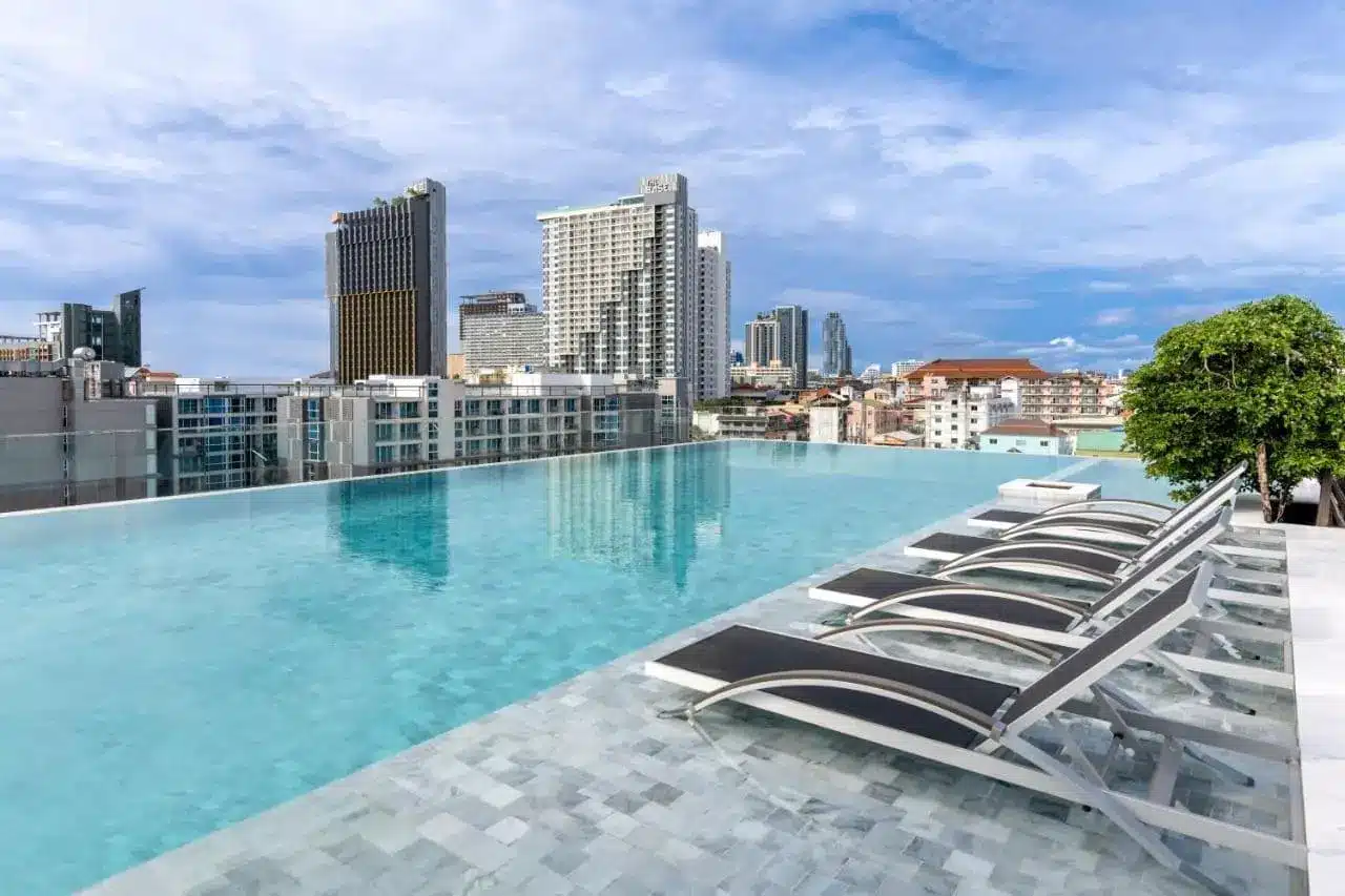 Amethyst Hotel Pattaya – Pool mit Sonnenliegen und Skyline-Blick.