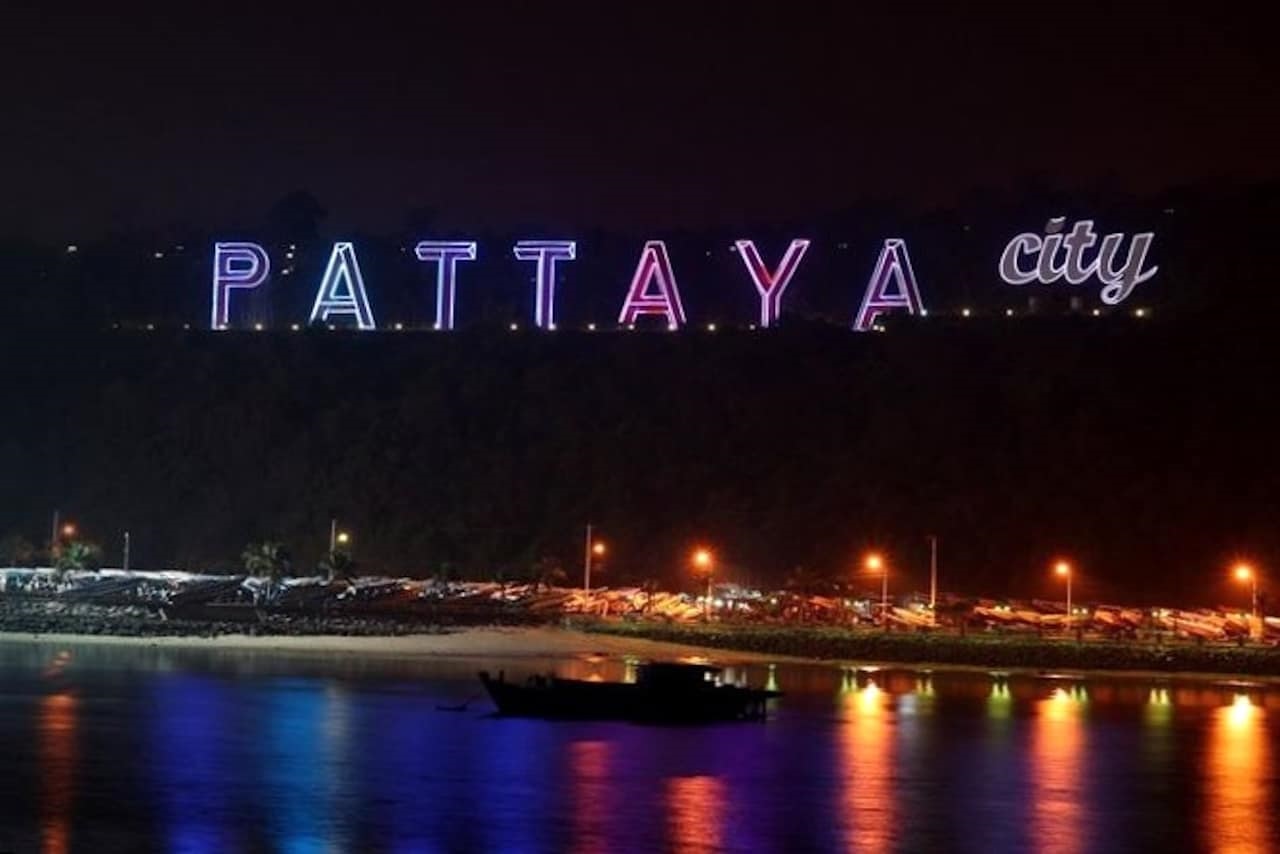 Pattaya City Schriftzug bei Nacht, beleuchtet, Blick vom Meer auf die Stadt Pattaya in Thailand.