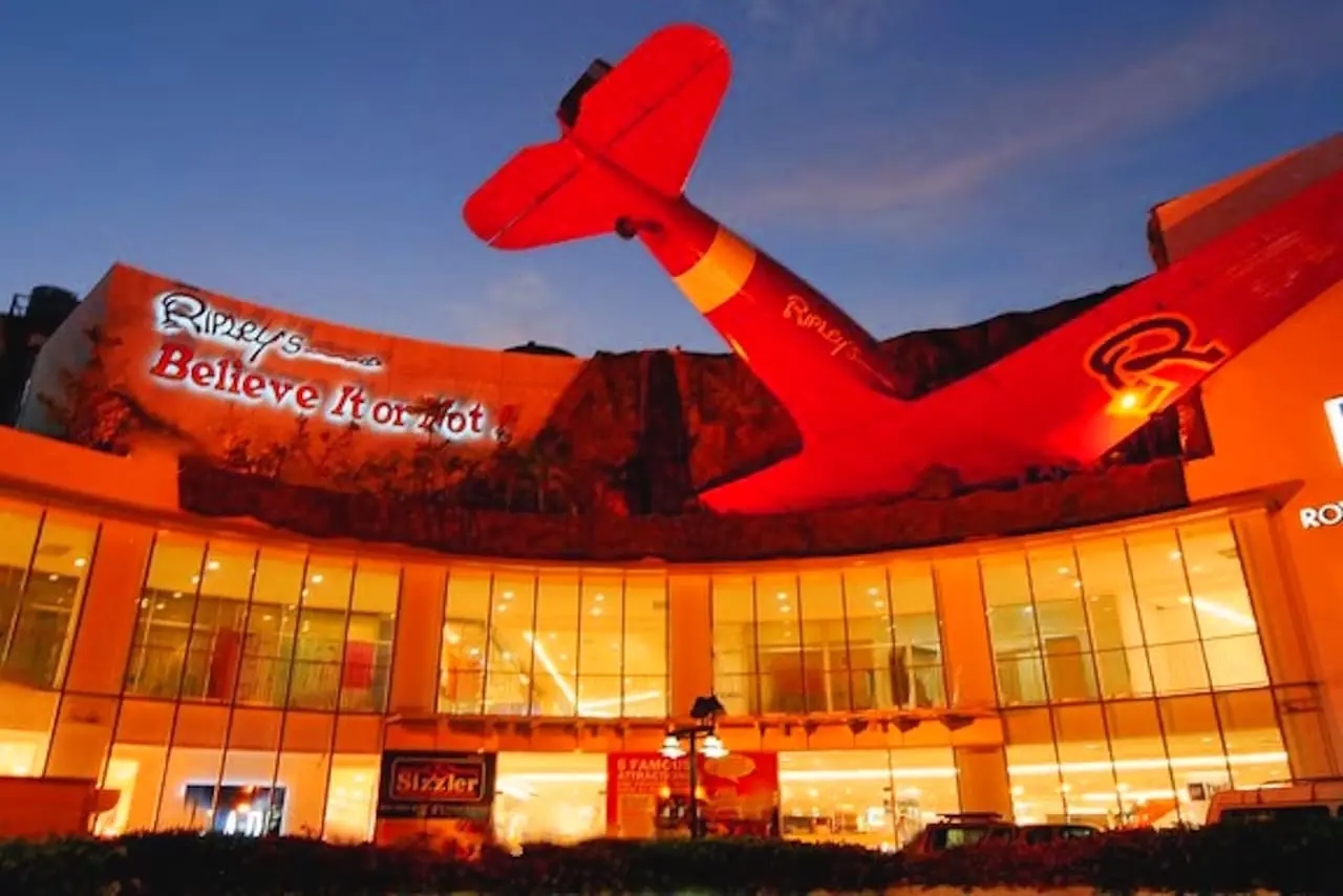 Die beleuchtete Fassade des Ripleys Believe It or Not im Royal Garden Plaza. Ein scheinbar abgestürztes Flugzeug ragt aus dem Gebäude.