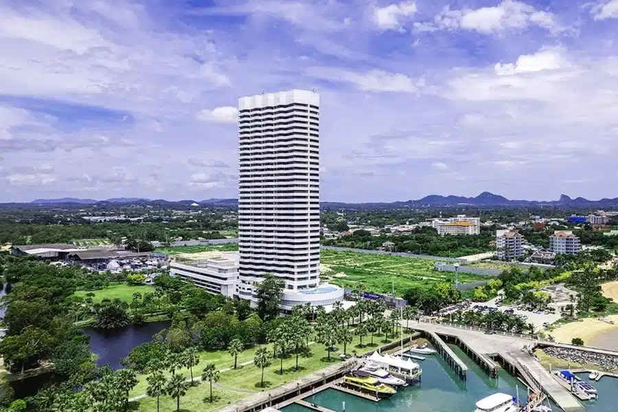 Blick auf den großen Außenpool des Ocean Marina Resort Pattaya Jomtien mit Meer im Hintergrund und tropischer Bepflanzung