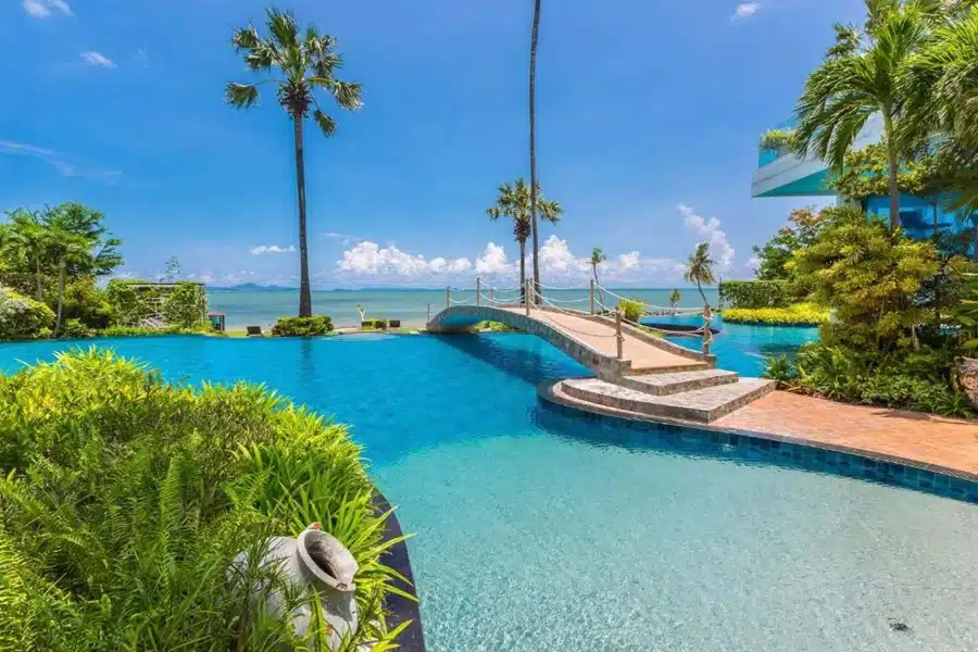 Poolanlage der Wongamat Boutique Apartments mit Meerblick und Sonnenliegen bei strahlendem Sonnenschein