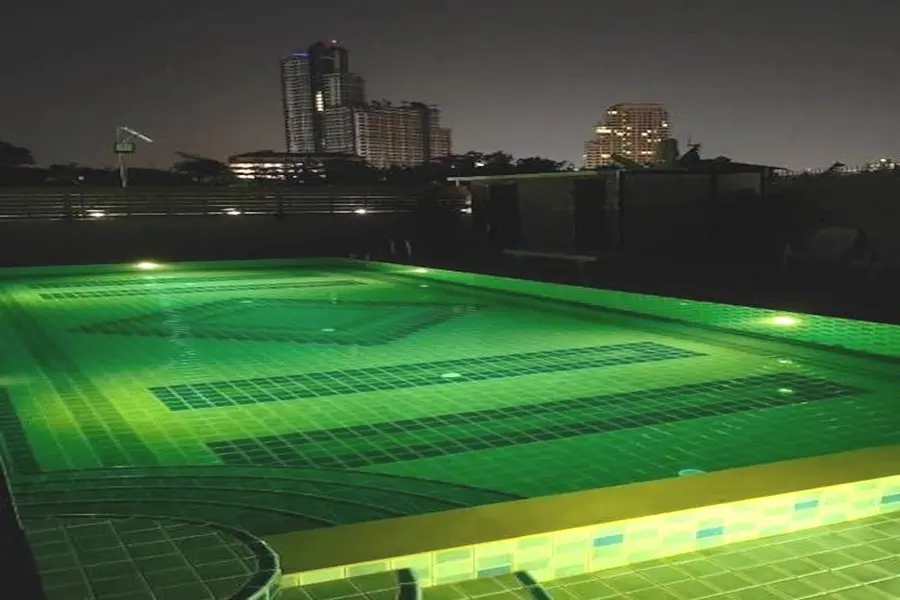 Orient House Pattaya – großer, beleuchteter Pool am Abend mit Sonnenliegen in zentraler Lage