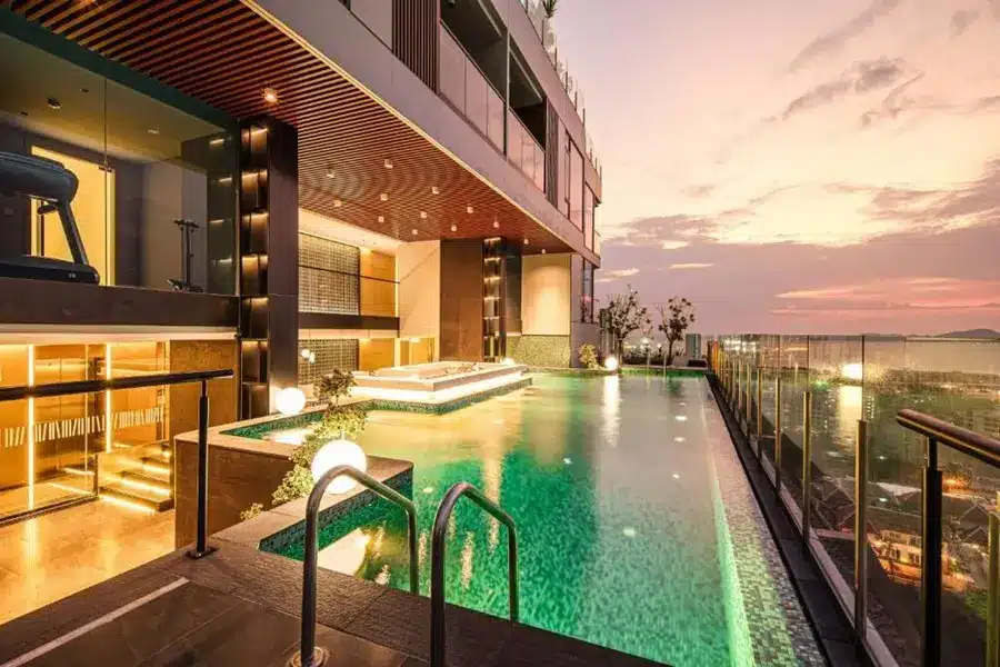 Beverly Mountain Bay Pattaya – beleuchteter Rooftop-Pool mit Sonnenliegen und Meerblick bei Sonnenuntergang